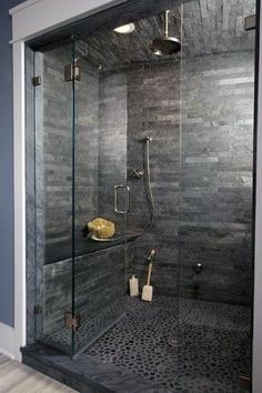 a walk in shower with black tile and glass walls