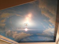 the ceiling is painted with clouds and a light fixture in the center, as well as a sky background