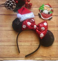 mickey mouse ears with santa clause hat and pine cones on wooden table next to christmas decorations