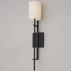 a black wall light with a white shade on it