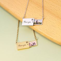 two personalized necklaces sitting on top of a wooden board