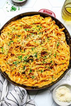 a skillet filled with pasta and parmesan cheese on top of a table