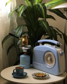 a blue toaster sitting on top of a table next to a cup of coffee