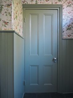 an empty room with a green door and wallpaper