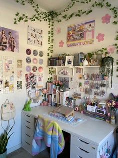 a desk with many pictures and plants on the wall above it, along with other office supplies