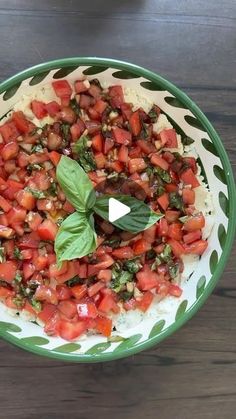 a green and white bowl filled with food on top of a wooden table