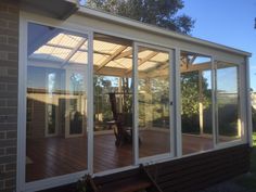 an enclosed patio with sliding glass doors on the side and wooden flooring in front