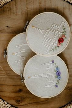 three embroidered hoops sitting on top of a wooden table