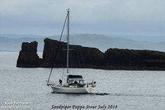 a sailboat in the water near some rocks