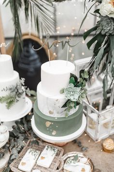 a white and green wedding cake with succulents