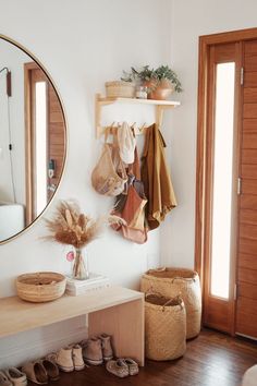 a room with shoes and baskets on the floor next to a wall mounted round mirror