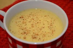 a red and white striped cup filled with soup on top of a red table cloth