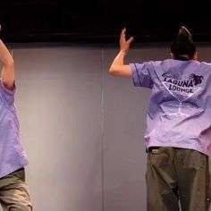 two people standing in front of a mirror with their hands up to the ceiling and one person wearing a purple shirt