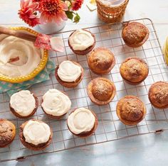 cupcakes with icing on a cooling rack next to a yellow teapot