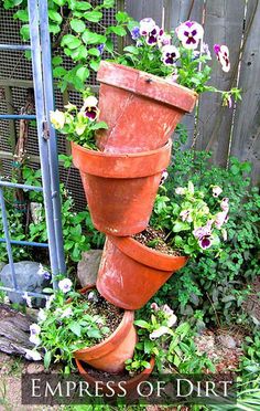 a tall planter filled with lots of flowers next to a fence