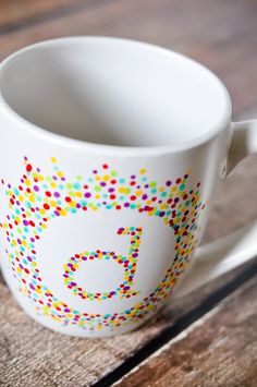 a white coffee cup with colorful sprinkles on it