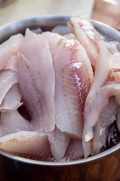 raw fish fillets sit in a metal bowl