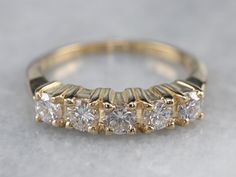 a gold ring with five diamonds on it