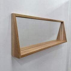 a mirror mounted to the side of a white wall next to a wooden framed object