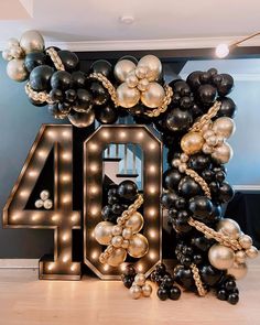 the number forty is made up of balloons and streamers in black, gold and white colors