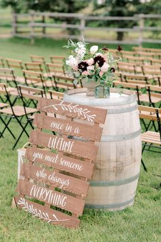 a wooden sign sitting on top of a grass covered field next to rows of chairs