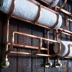 two rolls of toilet paper are hanging on the wall with copper pipes and white towels