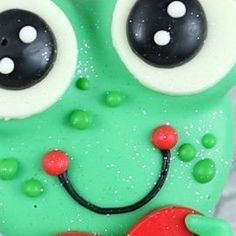 a close up of a green cake with eyes and a smile on it's face