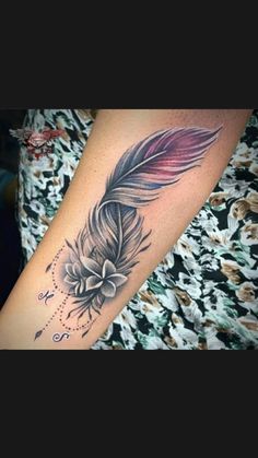 a woman's arm with a feather and flower tattoo on the left side of her arm