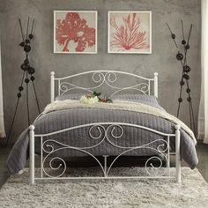 a white metal bed sitting in a bedroom next to two pictures on the wall above it