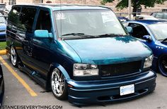 a blue van parked in a parking lot next to other cars