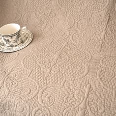 a cup and saucer sitting on top of a bed next to an empty plate