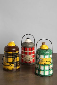 three tin canisters sitting on top of a wooden table