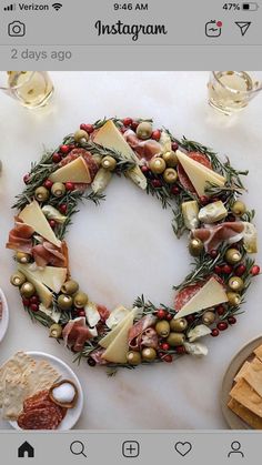 a christmas wreath made out of cheese, meats and olives on a table