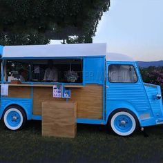 an old blue food truck is parked in the grass