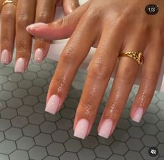 a woman's hands with pink manies and gold rings on her fingers, in front of a tiled floor