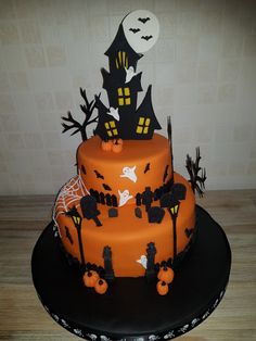 a three tiered halloween cake decorated with black and orange icing, spooky decorations and bats