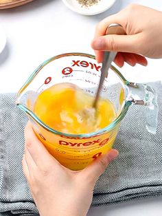 someone is mixing orange juice in a glass bowl