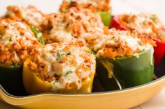 several stuffed peppers in a yellow casserole dish with cheese and meat toppings