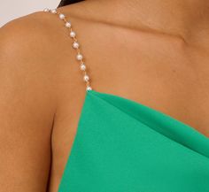 a woman wearing a green dress with pearls on the neck and shoulder chain, close up