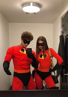 a man and woman dressed as the incredibles in front of a mirror looking at their cell phones