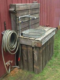 an old wooden box with a hose attached to it next to a red barn door