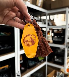 a hand holding a yellow keychain with a brown tassel