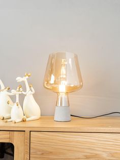 a lamp that is sitting on top of a wooden table next to two giraffe figurines