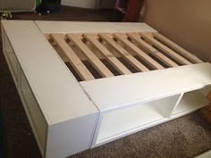 a white bed frame with wooden slats and drawers on the bottom part of it