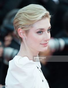 a close up of a person wearing a white dress and posing for a photo on the red carpet