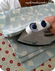 a person ironing fabric with an electric iron on top of it and another hand holding the iron