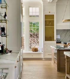 a kitchen with white cabinets and marble counter tops