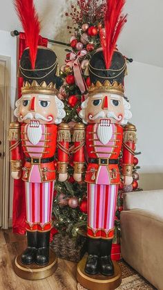 two red and gold nutcrackers are standing next to a christmas tree in a living room