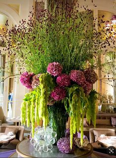 a large vase filled with lots of flowers on top of a table in a room