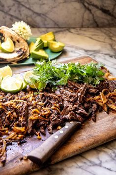 a cutting board topped with sliced up meat and veggies next to tortillas